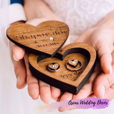 two wooden heart shaped rings are held in the palm of a bride and groom's hands