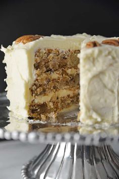 a piece of cake with white frosting and walnuts on the top is missing