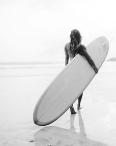 a woman holding a surfboard on top of a beach