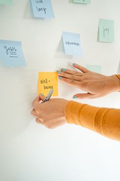 two hands holding sticky notes on a wall