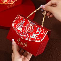 a person holding a red box with chinese writing on it and string attached to it