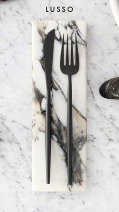 two forks and a knife on a marble plate with the words lusso written above it