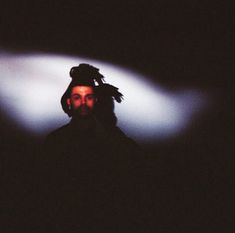 a man with dreadlocks standing in the dark