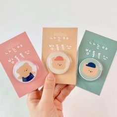 hand holding three small badges with korean characters on them