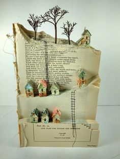 an altered book with houses and trees on it's pages, as if they were floating in the air