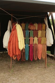 there are many different colors of yarn hanging from the clothes line in front of an awning