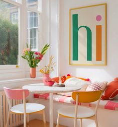 a white table and some chairs in a room with flowers on the window sill