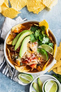 a bowl of chicken tortilla soup with avocado and cilantro