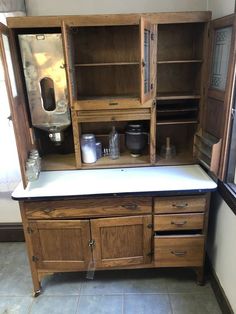 an old fashioned wooden kitchen cabinet with white counter top and drawers on the bottom shelf