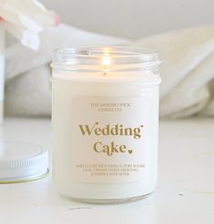 a white candle sitting on top of a table next to a bottle of wedding cake