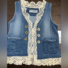 a denim vest with white lace and buttons