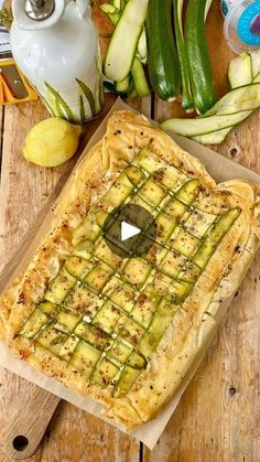 a pizza sitting on top of a cutting board next to zucchini and other vegetables