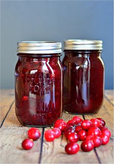 two jars filled with cranberry sauce sitting on top of a wooden table