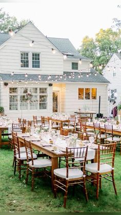 an outdoor dining area with tables and chairs set up in front of a large white house