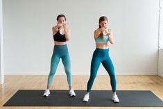 two women doing yoga poses on mats in an empty room