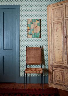 a chair sitting in front of a blue door next to a wall with a painting on it