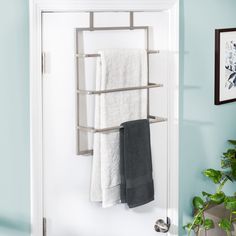 a towel rack in the corner of a bathroom with towels hanging on it and a potted plant next to it