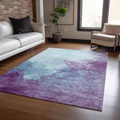 a living room filled with furniture and a purple rug on top of a hard wood floor