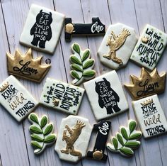 decorated cookies are arranged in the shape of animals and crowns on a white wooden surface