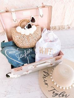 an open suitcase sitting on top of a floor next to a straw hat and purse