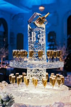 a table topped with lots of champagne glasses and a clock on top of the cake