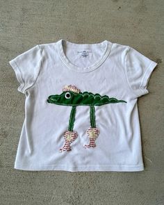 a white t - shirt with a green alligator on it's chest and feet