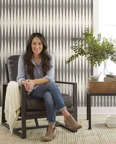 a woman sitting in a chair with her legs crossed, smiling at the camera and wearing boots