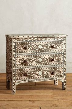 a white and brown chest of drawers sitting on top of a wooden floor