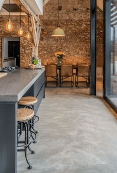 an open kitchen and dining area with brick walls, flooring and exposed ceiling beams