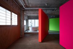 an empty room with red, green and pink partitions in the wall next to a bathtub