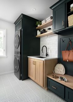 a washer and dryer in a small room with black cabinets, white tile flooring and open shelving