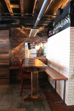 the inside of a restaurant with wooden tables and benches in front of bricked walls