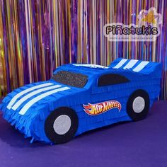 a blue car made out of paper sitting on top of a purple tablecloth covered floor