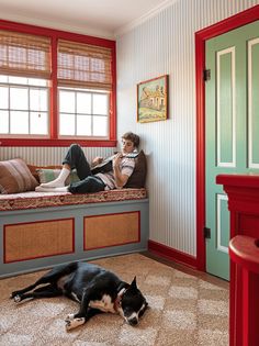 a man laying on top of a bed next to a black and white dog in a room