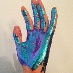 a person's hand covered in blue and green paint