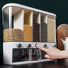 a person pressing buttons on a coffee maker with cereals and beans in front of them