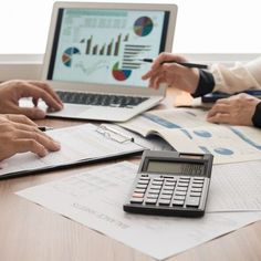 three people sitting at a table with papers and calculator in front of them