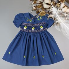 Hand-Smocked Embroidered Dress in Gorgeous Deep Blue Color for your Baby Girl. Beautifully Crafted Garment that Exudes Elegance and Charm. This Vintage Inspired Style is updated with Cheerful Colors and Adorable Details : - Meticulously Smocked Bodice.  - Pink White Zik Zak Hand-Smocking Across the Chest and Final Touch with Boat of Yellow Roses.  - Peter Pan Collar with Embroidery.  - Puffy Sleeves with narrow cuffs.  - Matching Rose-Buds Embroidered at Hem. - Tiny Matching Buttons to assist wi Girl Beautifully, Navy Formal Dress, Mini Baskets, Celebration Dress, Hand Smocking, Portrait Dress, Girls Special Occasion Dresses, Birthday Girl Dress