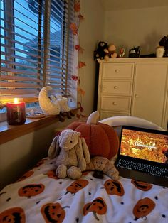 stuffed animals sit on the bed in front of a laptop computer with halloween themed decorations