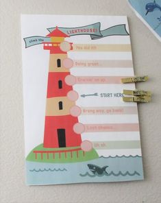 a clipboard with a lighthouse on it next to some magnets and paper clips