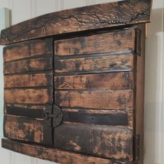 an old wooden wall hanging on the side of a white wall with wood planks