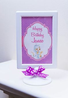 a happy birthday card with a purple bow on a white table next to a pink polka dot ribbon