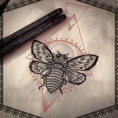 a drawing of a butterfly on paper next to a marker and pen with the image of a moth drawn on it