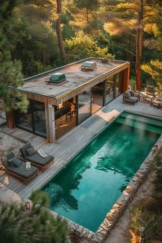 an aerial view of a house with a pool in the foreground and lounge chairs around it