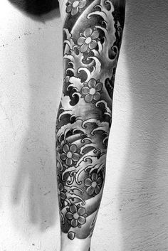 a black and white photo of a man's arm with flowers on it