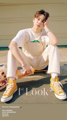 a young man sitting on the ground wearing yellow sneakers