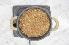 a pan filled with rice and vegetables on top of a counter next to a spatula