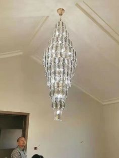 a man standing next to a woman under a chandelier in a living room