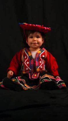 a small child wearing a red hat sitting on top of a black surface