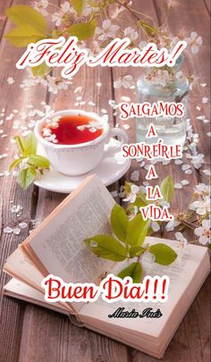 an open book sitting on top of a wooden table next to some flowers and leaves